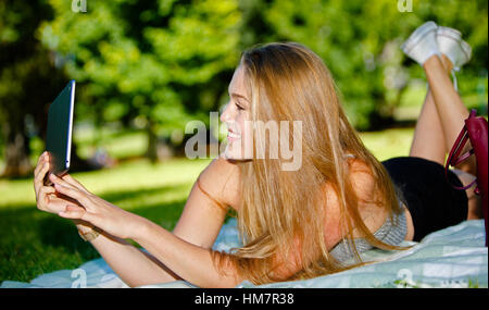 Glückliches Mädchen nimmt Selfie mit Tablet im freien Stockfoto