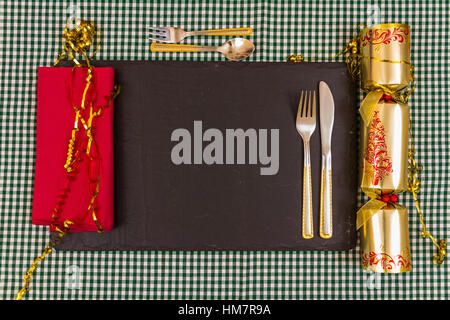 Platz für Xmas Dinner, Messer, Gabel, Christmas Cracker, Serviette auf Schiefer Matte gelegt. Stockfoto