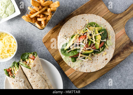 Gegrilltes Hühnerfleisch wraps mit Karotte, Käse, Avocado und Spinat. Mit Pommes Frites auf der Seite. Stockfoto