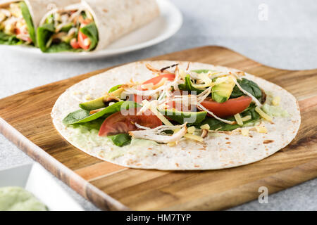 Gegrilltes Hühnerfleisch wraps mit Karotte, Käse, Avocado und Spinat. Mit Pommes Frites auf der Seite. Stockfoto