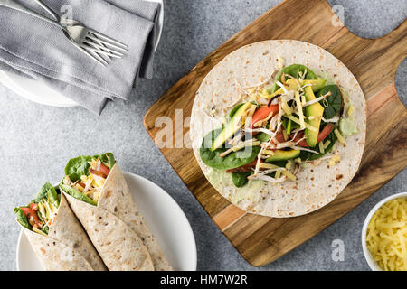 Gegrilltes Hühnerfleisch wraps mit Karotte, Käse, Avocado und Spinat. Mit Pommes Frites auf der Seite. Stockfoto