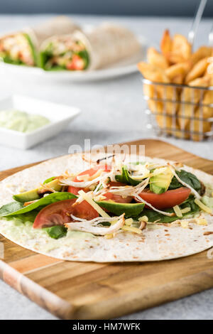 Gegrilltes Hühnerfleisch wraps mit Karotte, Käse, Avocado und Spinat. Mit Pommes Frites auf der Seite. Stockfoto