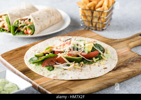 Gegrilltes Hühnerfleisch wraps mit Karotte, Käse, Avocado und Spinat. Mit Pommes Frites auf der Seite. Stockfoto