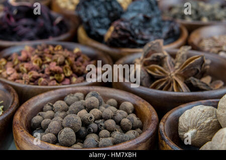 Piment Beeren unter andere Gewürze in kleinen braunen Schalen Stockfoto