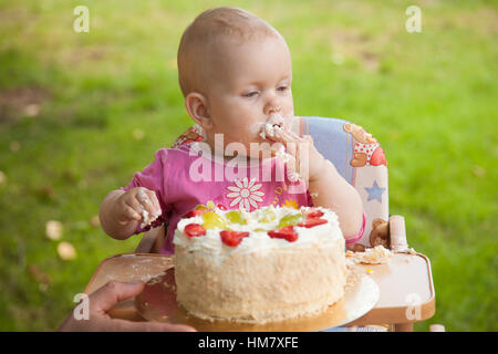 Ein Baby Essen Geburtstagskuchen mit seinen Händen Stockfoto