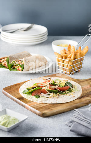 Gegrilltes Hühnerfleisch wraps mit Karotte, Käse, Avocado und Spinat. Mit Pommes Frites auf der Seite. Stockfoto