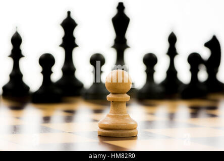 Weiße Bauern gegen eine Übermacht der schwarzen Figuren auf einem Schachbrett. Selektiven Fokus. Stockfoto