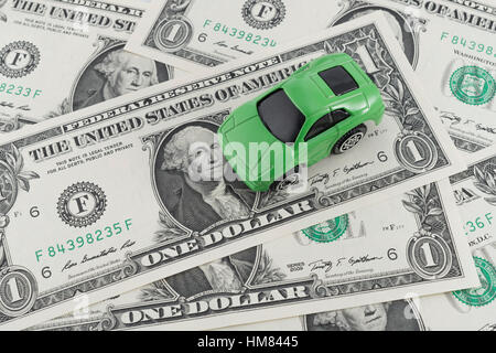 Kleine grüne grüne Spielzeugauto auf uns 1 Dollar/1 $ Rechnungen. Als Metapher für die Kosten des Autofahrens und Benzin in den USA und die Green Fuel, grüne Wirtschaft. Stockfoto