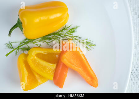 Gelb und orange Mini-Paprika auf einem Teller, in Scheiben geschnitten als Zutat verwendet werden Stockfoto