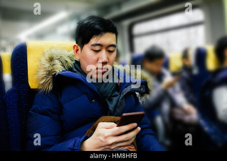 Asiatischer Mann mit Smartphone auf den öffentlichen Zug im winter Stockfoto