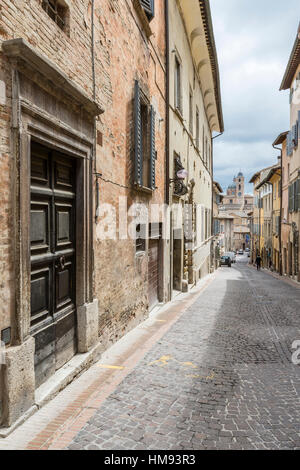 Eine mittelalterliche Gasse von der Bergstadt mit Piazza Duca Federico in den Hintergrund, Urbino, Provinz von Pesaro, Marken, Italien Stockfoto