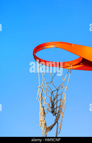 Nahaufnahme von einem Basketballkorb mit einem zerrissenen Netz vor einem blauen Himmel. Stockfoto