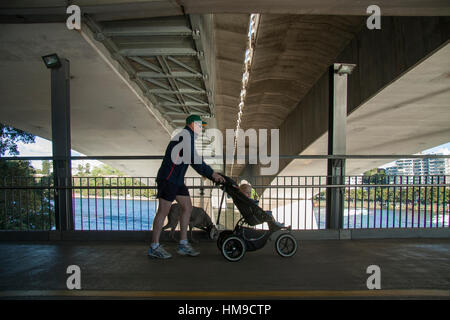 Man drückt ein Baby in einem Buggy unter einer Brücke Stockfoto