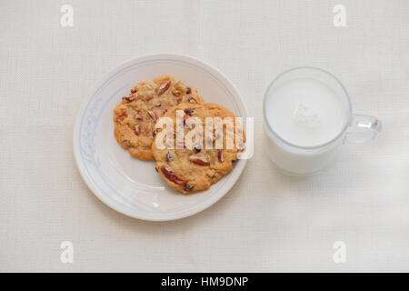 Zwei warme, frische Pecan Schokoladenkekse auf eine Untertasse mit einer Tasse Milch. Studio im Haus. USA. Stockfoto