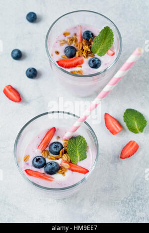 Gesunde Heidelbeeren und Erdbeeren Smoothies, garniert mit frischen Beeren Müsli und Minze Blatt mit cocktail-Rohr Stockfoto