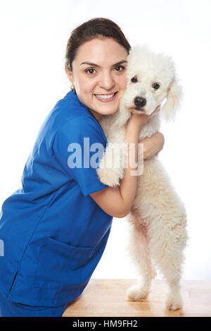 Tierarzt Doktor Mädchen umarmt eine weiße französische Pudelhund Stockfoto