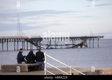 Besucher auf Cowlyn Bay auf der Suche nach Ansicht Teile von Victoria Pier ins Meer während des Tages mit mehr erwartet gefallen Stockfoto