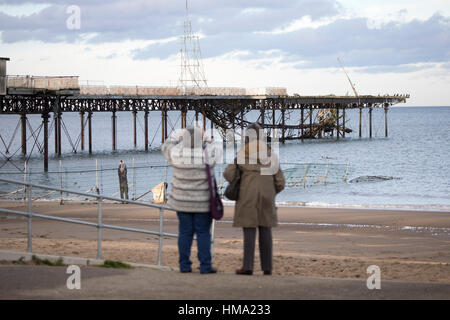 Besucher auf Cowlyn Bay auf der Suche nach Ansicht Teile von Victoria Pier ins Meer während des Tages mit mehr erwartet gefallen Stockfoto