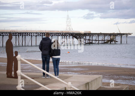 Besucher auf Cowlyn Bay auf der Suche nach Ansicht Teile von Victoria Pier ins Meer während des Tages mit mehr erwartet gefallen Stockfoto