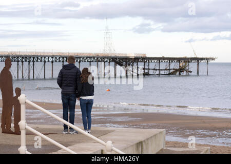 Besucher auf Cowlyn Bay auf der Suche nach Ansicht Teile von Victoria Pier ins Meer während des Tages mit mehr erwartet gefallen Stockfoto