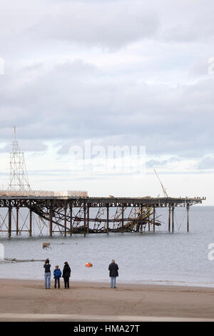 Besucher auf Cowlyn Bay auf der Suche nach Ansicht Teile von Victoria Pier ins Meer während des Tages mit mehr erwartet gefallen Stockfoto