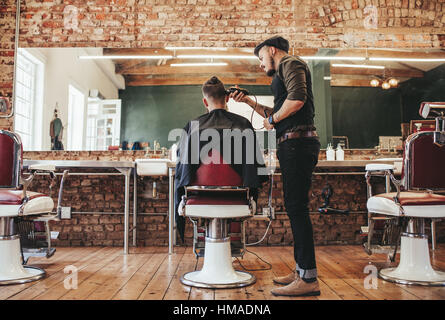 Rückansicht Schuss gut aussehend Friseur Haare schneiden von männlichen Kunden. Friseur Portion Client beim Friseur. Stockfoto