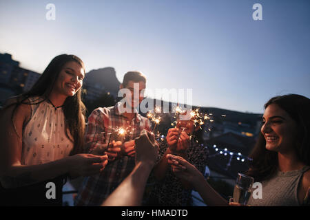 Gruppe von Freunden genießen auf der Dachterrasse-Party mit Wunderkerzen. Junge Menschen genießen Silvester. Stockfoto