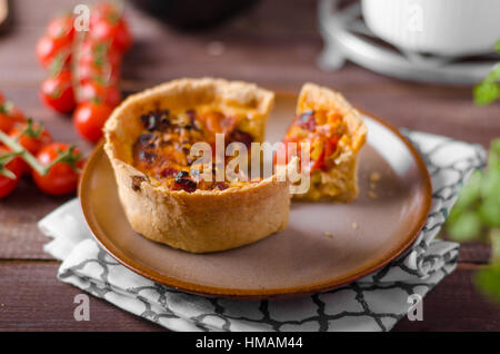 Mini-Quiche mit Würstchen, Mini-Tomaten und Kräutern Stockfoto