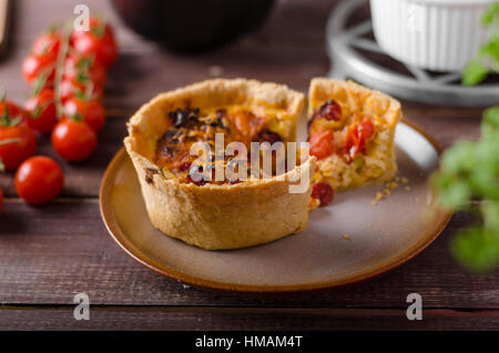 Mini-Quiche mit Würstchen, Mini-Tomaten und Kräutern Stockfoto