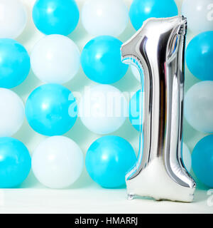 Glänzenden ersten Geburtstag Ballon mit blauen und weißen Luftballons Hintergrund. Stockfoto