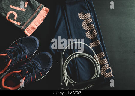 Draufsicht der Frauen ist dunkel blau und rosa Training Outfit mit einem Springseil auf schwarzem Hintergrund Stockfoto