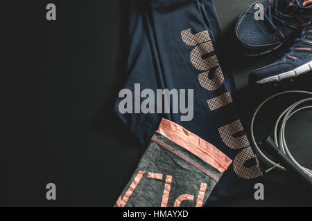 Draufsicht der Frauen ist dunkel blau und rosa Training Outfit mit einem Springseil auf schwarzem Hintergrund Stockfoto