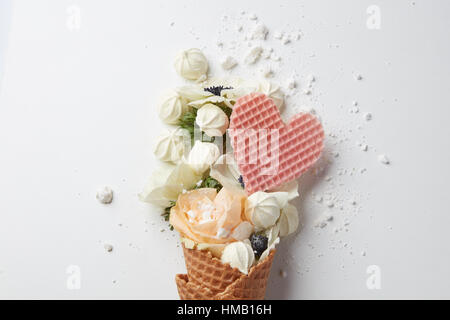 Schöne Blume im Eis mit Baiser und Waffel Herz auf weißem Hintergrund Stockfoto