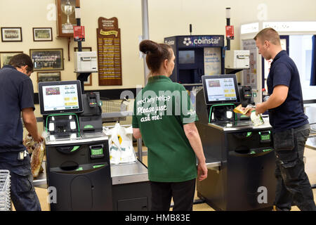 Shop Assistant hilft Kunden beim Self Checkout im Supermarkt Stockfoto