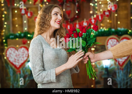 Valentinstag-Konzept. Frau zu feiern. Liebhaber präsentieren einander Strauß roter Rosen Stockfoto