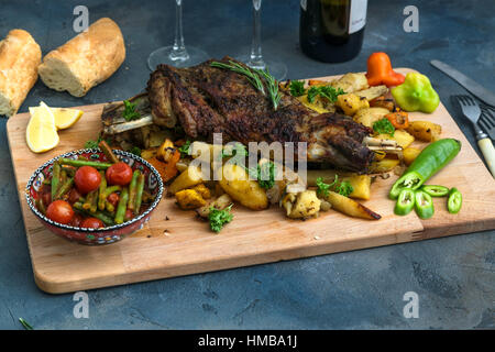 Gebratene Lammschulter auf gebackenen Kartoffeln und Karotten, Holzbrett, Ansicht von oben Stockfoto