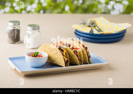 Mexikanische Tacos mit Rindfleisch, Cheddar-Käse, Tomaten, Bohnen und Salsa DIP Stockfoto