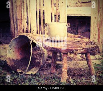 alten gebrochenen Eimer und einen Aluminium-Pfanne auf den Holzstuhl, der vom Landwirt verwendet wurde, um die Milch der Kühe zu melken Stockfoto