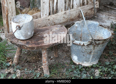 verlassene Scheune pan eine alte gebrochene Eimer und ein Aluminium auf dem hölzernen Stuhl, der vom Landwirt verwendet wurde Stockfoto