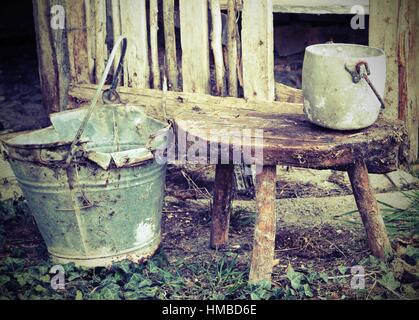 alte Scheune pan eine alte gebrochene Eimer und ein Aluminium auf dem hölzernen Stuhl, der vom Landwirt verwendet wurde Stockfoto