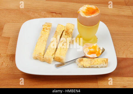 Weich gekochtes Ei und Toast Soldaten auf einer Platte auf eine hölzerne Küchenarbeitsplatte Stockfoto