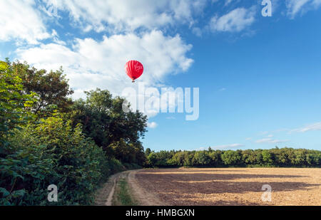 Natives Heißluftballon schwebt über neu gepflügten Feld und Bäume in der Chilterns an einem Sommerabend Stockfoto