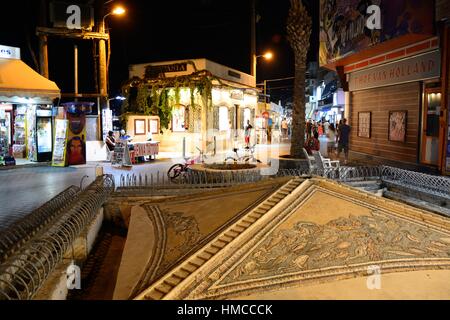 Blick auf den Roman Sarakino Brunnen entlang der Uferpromenade in der Nacht mit Souvenirläden auf der Rückseite, Hersonissos, Kreta, Griechenland, Europa. Stockfoto