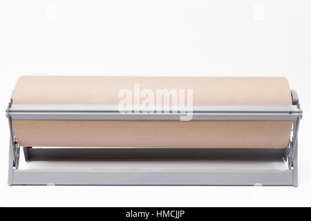 Rolle des braunen Kraftpapier und Papierschneider auf weißem Hintergrund Stockfoto