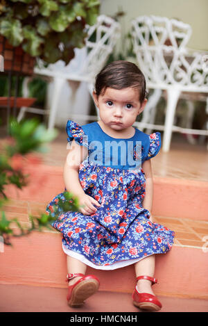 ein kleines Mädchen Kind Sit-on-Schritte im Kleid Stockfoto