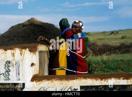 Ein Ndebele-Frau und ein Mann dekorieren ein Rondavel (runden oder ovalen Traditionshaus) in einem Dorf, Südafrika. Stockfoto