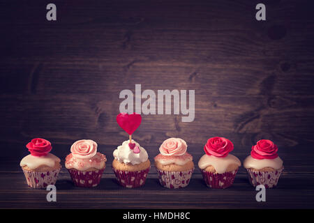 Kleine Muffins mit Rosen in einer Reihe Stockfoto