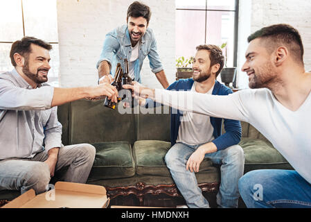 Freudige positive Männer Flaschen Klirren Stockfoto