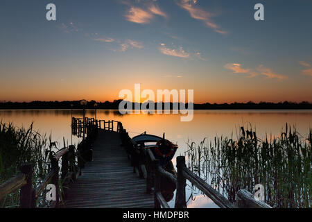 Schöner Sonnenuntergang am kleinen Dock in "Shabla See". Epische Wolken und Stillgewässer beschossen goldene Stunde. Einzigen Boot noch im Wasser. Stockfoto