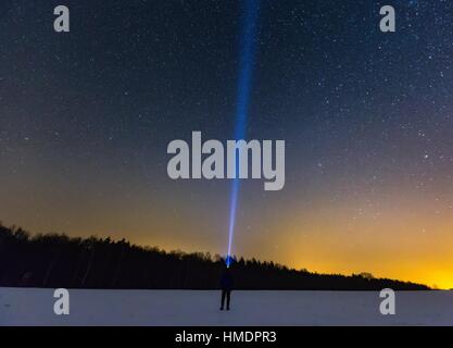 Mann mit Kopf Taschenlampe zeigt Licht am Sternenhimmel. Nachtlandschaft Stockfoto